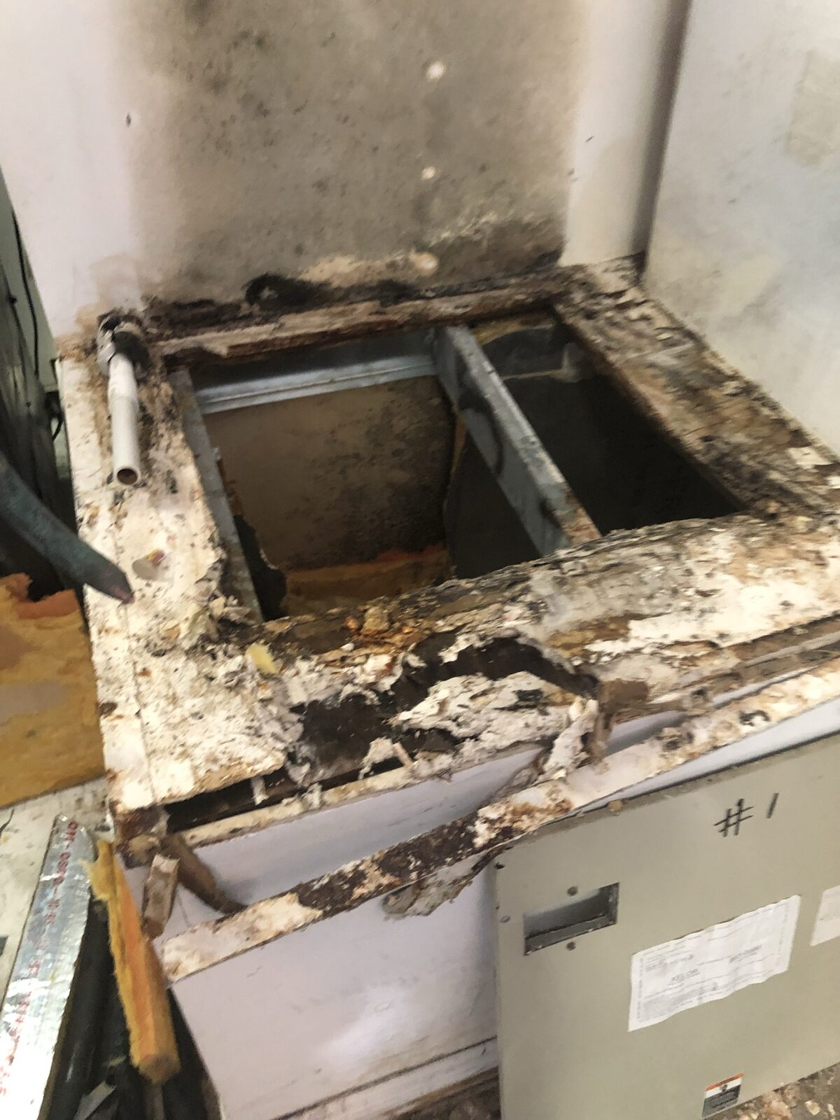 Rusted air handler base with visible water staining and corrosion