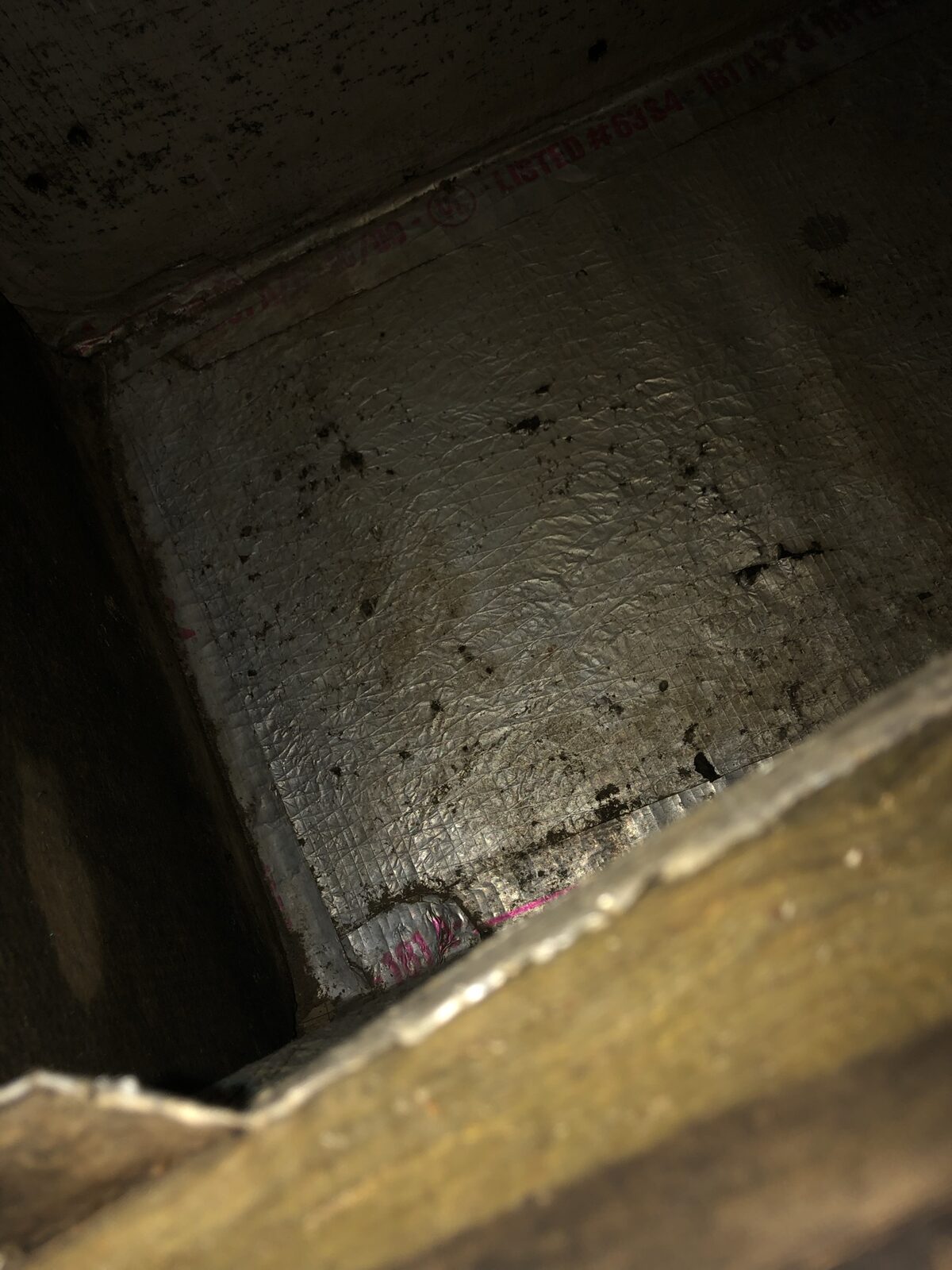 Interior of a return-air plenum caked with years of dust and grime