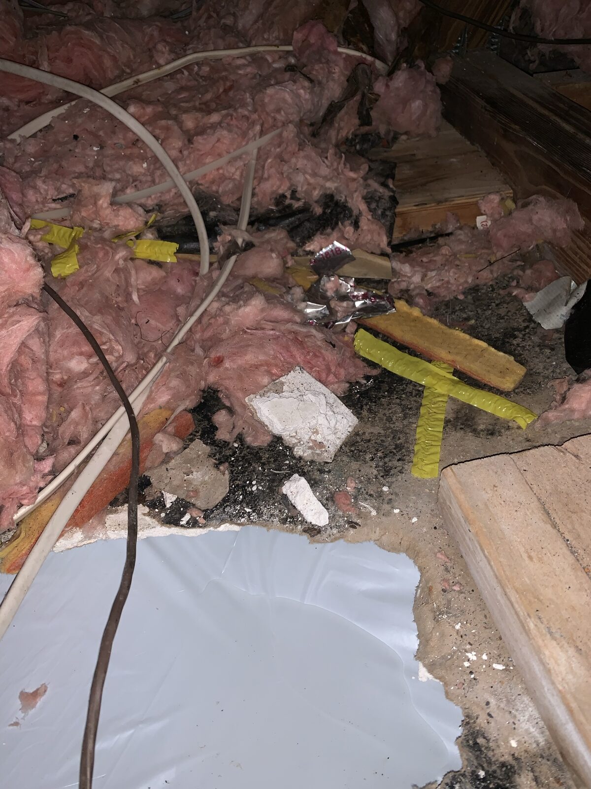 Attic floor strewn with displaced insulation, framing and debris after rodent and water damage