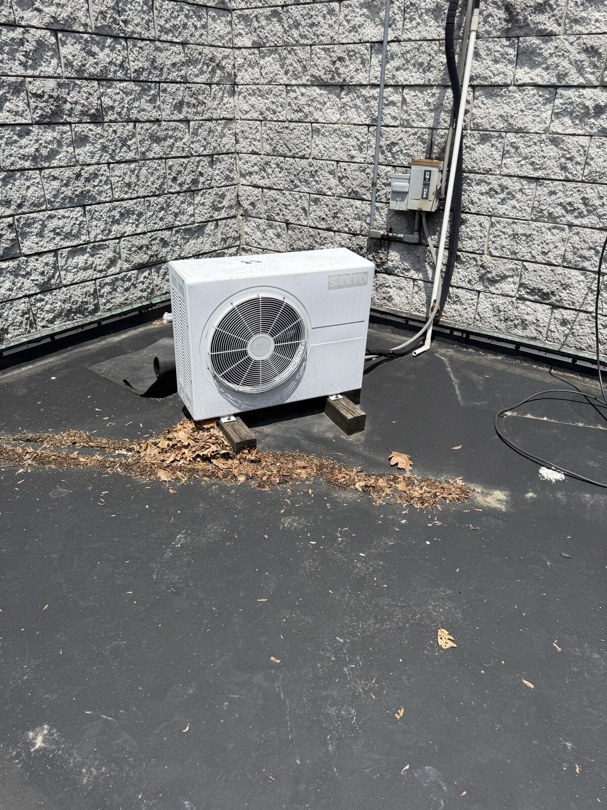 Ductless mini-split condenser sitting on a rooftop membrane