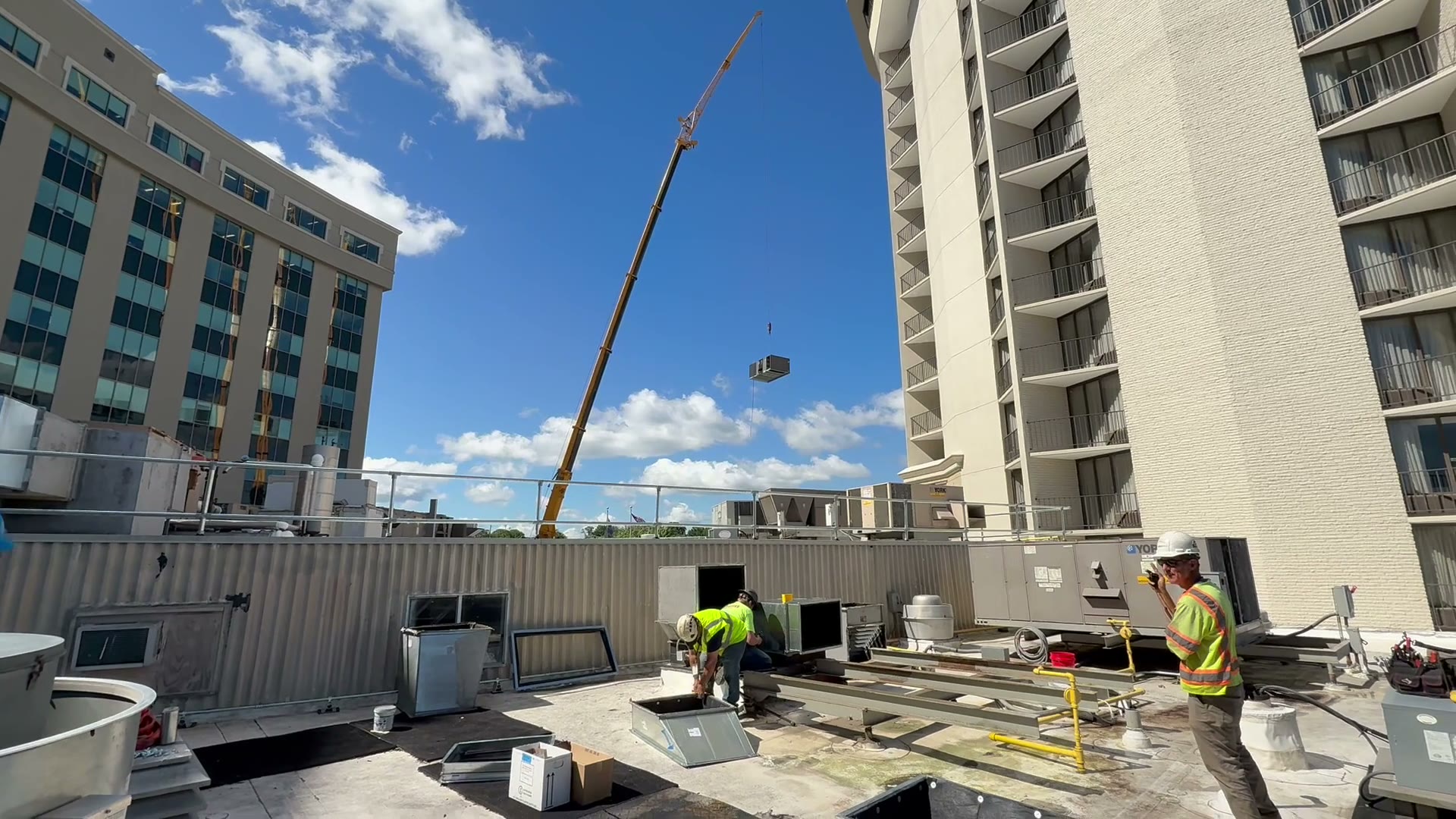 The 100-ton crane boom fully extended, the old 20-ton York unit airborne over the casino rooftop with hi-vis crew watching the pick
