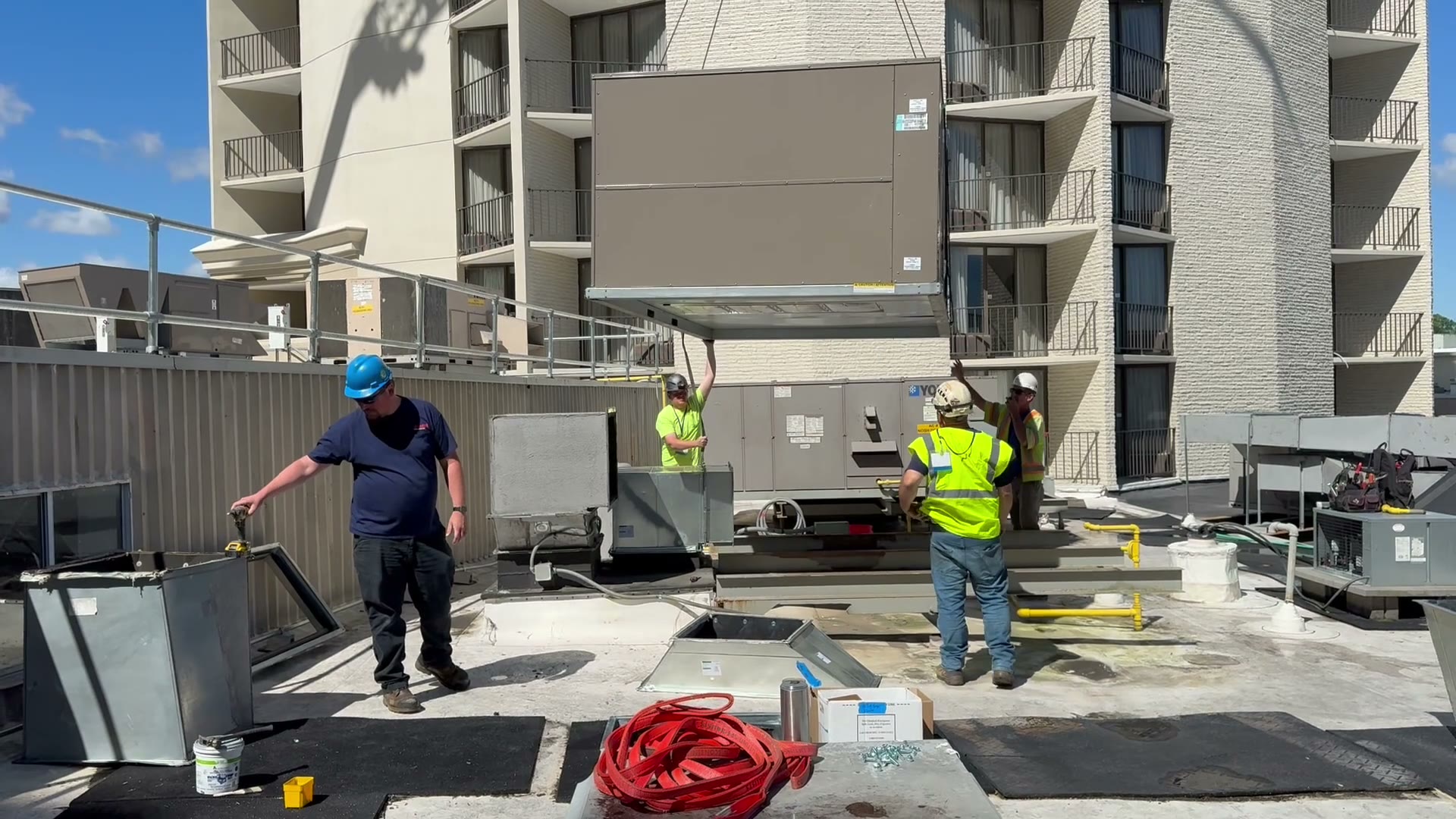 The new York rooftop unit being lowered onto the curb while the crew guides it into place by hand